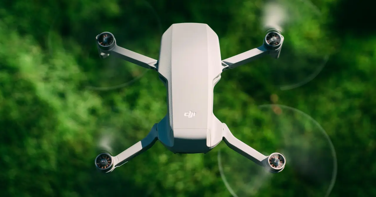 Компактный складной дрон DJI в полёте над зеленью
