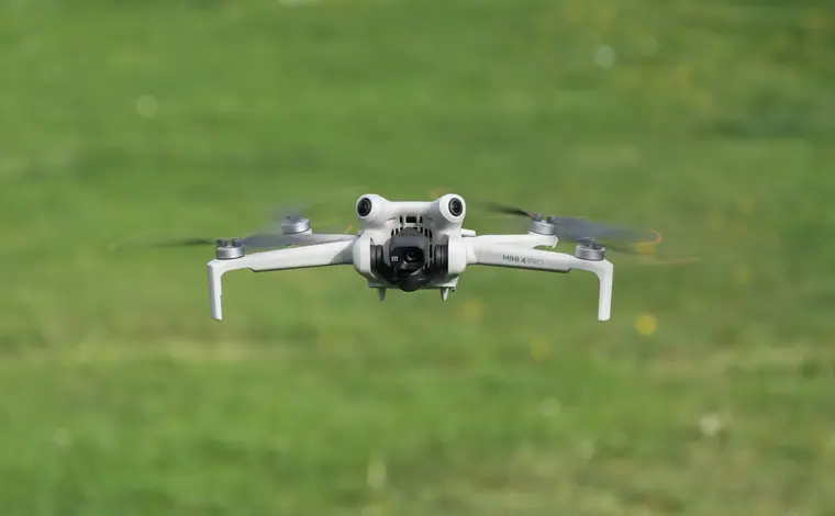 Квадрокоптер DJI Mini 4 Pro зависает низко над травой